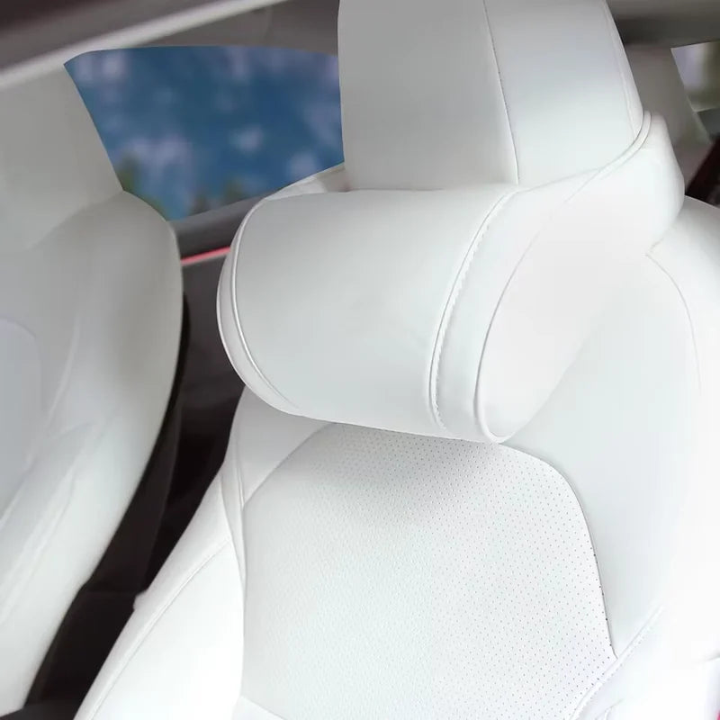 Close-up of white neck pillow strapped to a white Tesla headrest