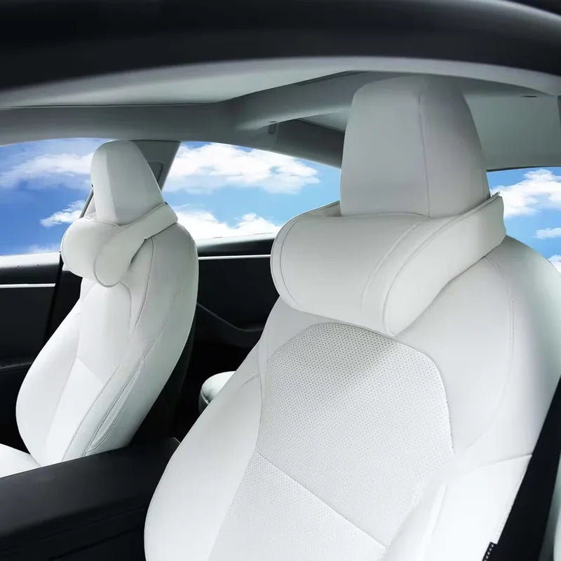 White neck pillows on white Tesla front seats